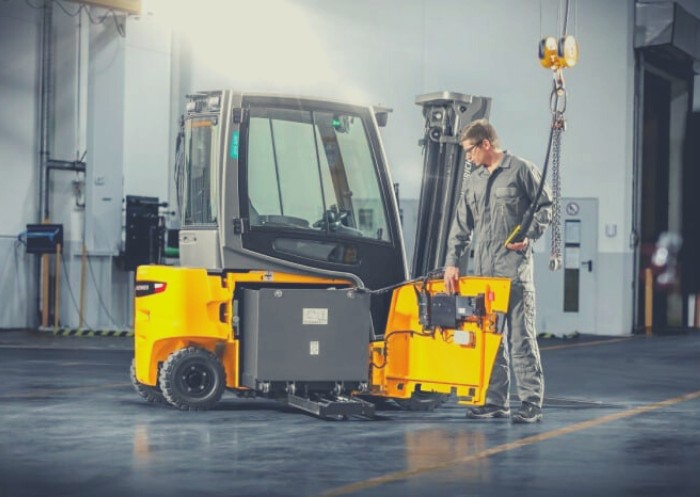 Ein Mann entfernt den Akku eines Gabelstaplers mithilfe einer Krananlage