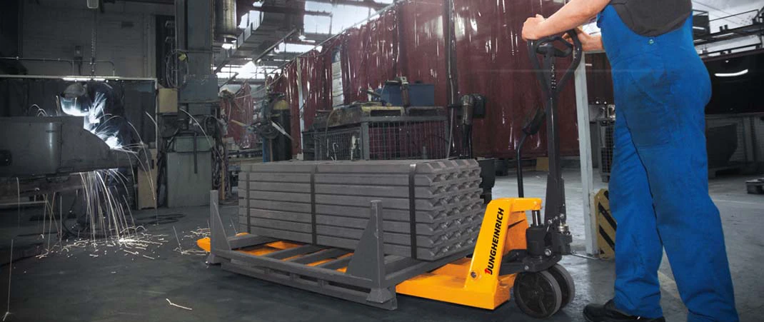 Mann bedient Hubwagen in einer Produktionshalle