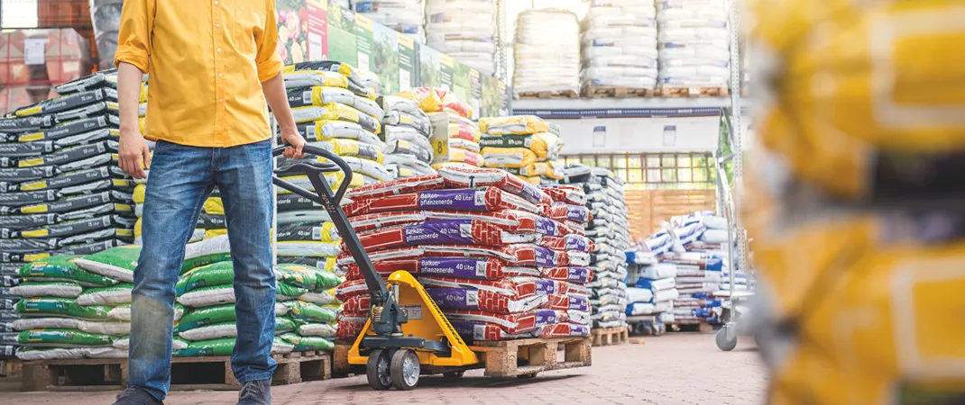 Mann zieht beladenen Hubwagen