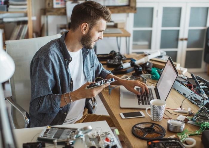 Mann arbeitet in Werkstatt am Laptop