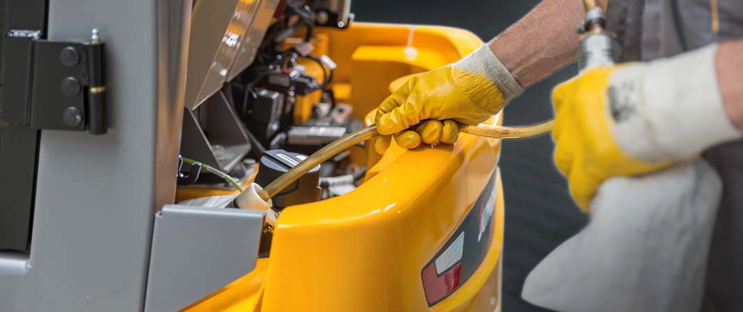 Eine Person füllt Hydrauliköl in einen Gabelstapler